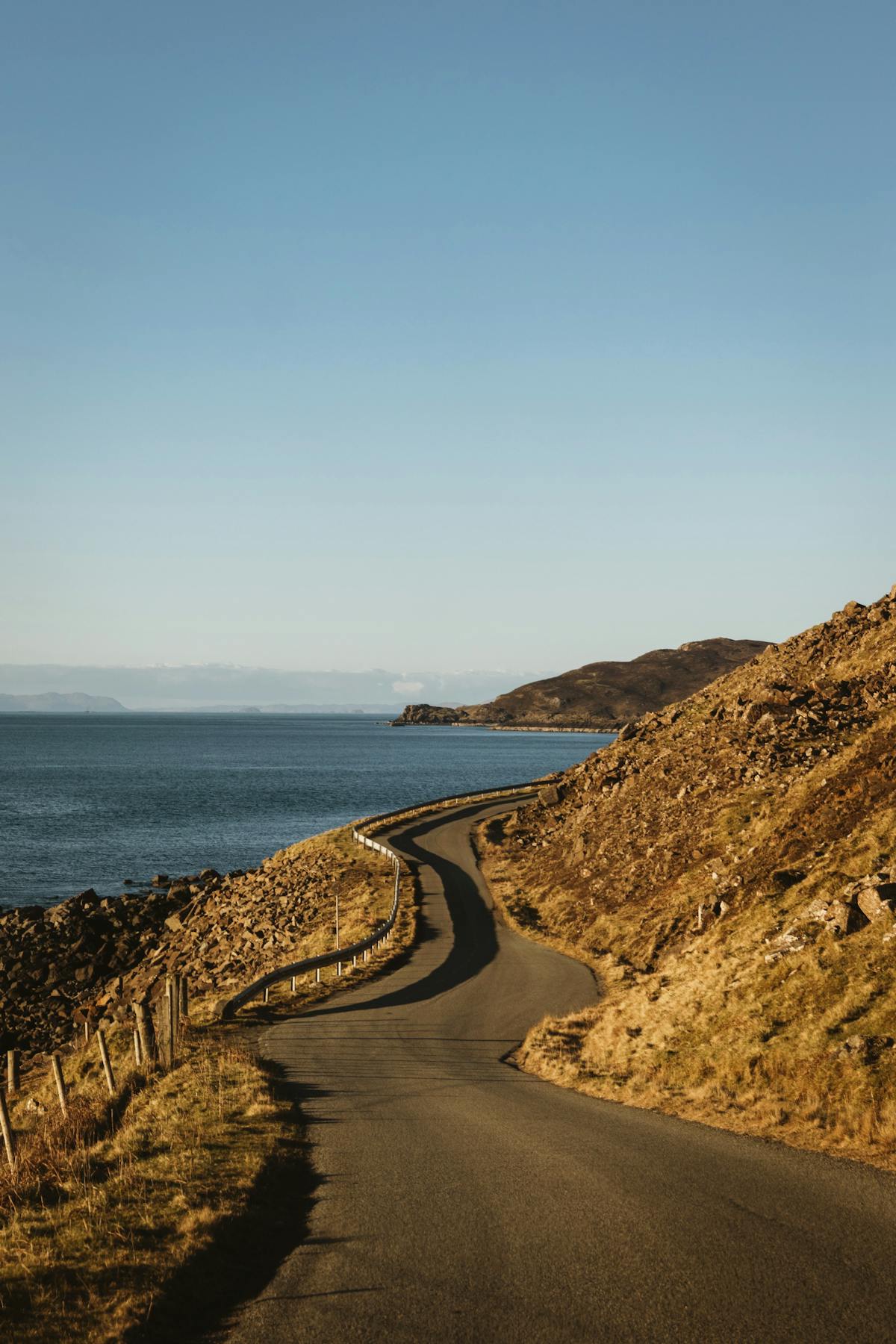 A winding coastal road along Scotland's North Coast 500 route with mountains and sea views
